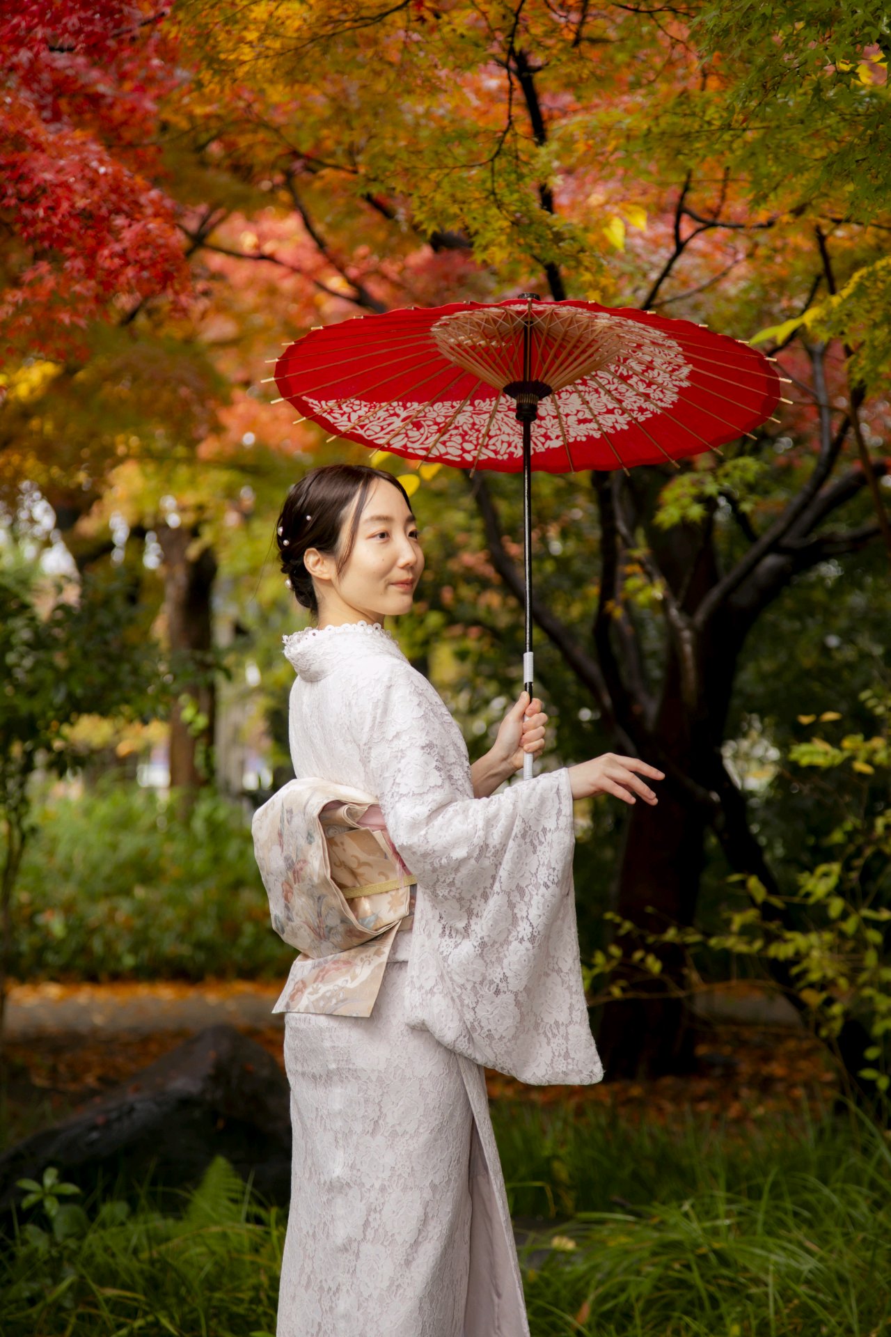 紅葉の中で和傘を持つ着物姿